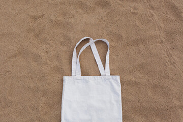 White cotton or mesh bag on beach sand background. Zero waste, no plastic, eco friendly shopping,...