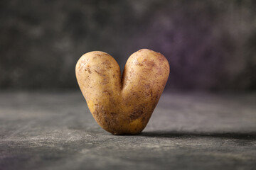 Close-up einer Kartoffel in Form eines Herz vor dunklem Studio-Hintergrund