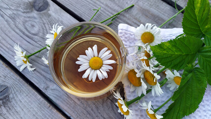 Chamomile tea close-up on a wooden background. Summer still life with wildflowers and chamomile...