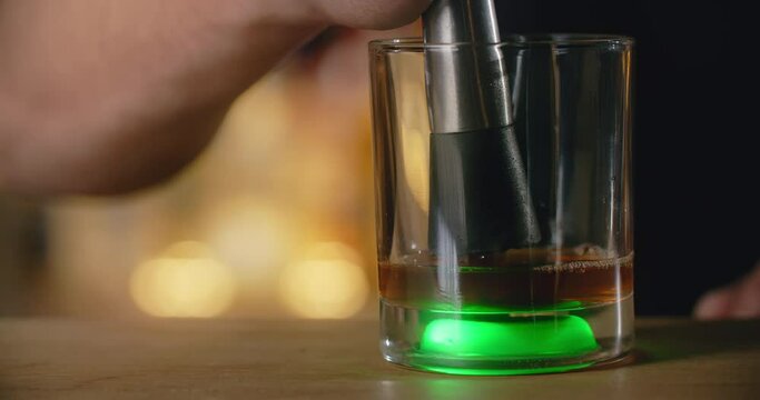 Bartender uses mudler for crushing the lump shugar in the cocktail glass on the bar counter, making the coctail at the bar, 4k Prores HQ