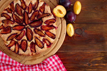 plum cake and plums on wood background