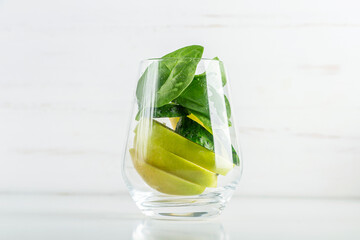 Glass with green smoothie and glass with ingredients spinach, apple, cucumber. Home cooking. Vegan healthy detox eating, dietary and weght loss drink.