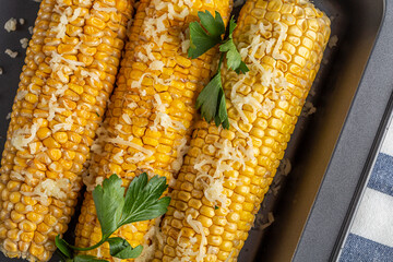 Recipe homemade cooking. Mexican Elote Corn sprinkled with cheese or parmesan and cilantro on baking sheet. Close up.