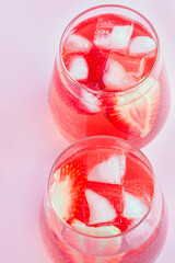 Two glasses of Cooling strawberry Sangria with sparkling wine, strawberry, ice cubes in champagne glass. Refreshing summer alcoholic cocktail drink , lemonade or ice tea.