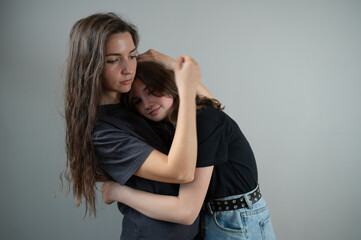 Pretty girls hugging isolated on gray studio background. Mother and doughter