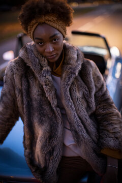 Portrait confident beautiful young woman in fur coat at convertible