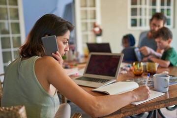 Woman working from home at dining table with family