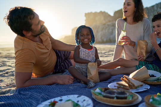 Portrait cute toddler girl enjoying picnic with family on beach