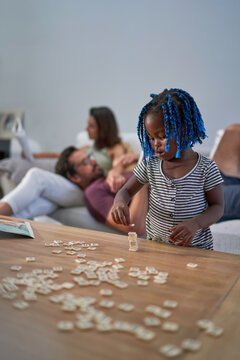 Cute toddler girl stacking scrabble tiles on coffee table