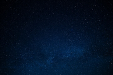 Night starry sky. Deep saturated dark blue color. Small stars twinkle far away in the sky. There is no one in the photo. There is a place for your signature. Background. Wallpaper. Texture.
