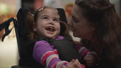 close up of disabled child in wheelchair playing and having fun with adorable mother at home.