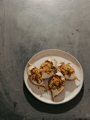 Stuffed blue crabs on a white plate and gray background