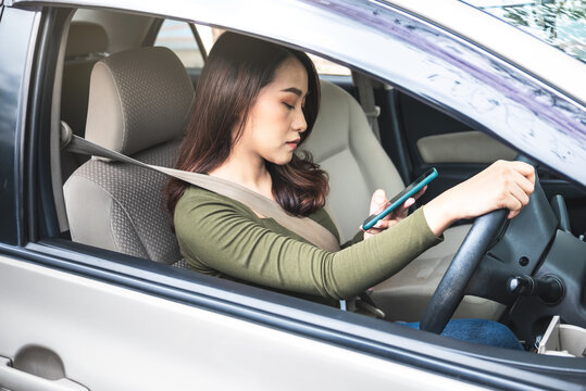 Portrait images of Asian attractive woman Using mobile phone while driving,  concept to Causes of accidents in driving and accident insurance