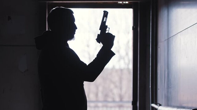 A man pulls the shutter of his gun and twisting it in his hand