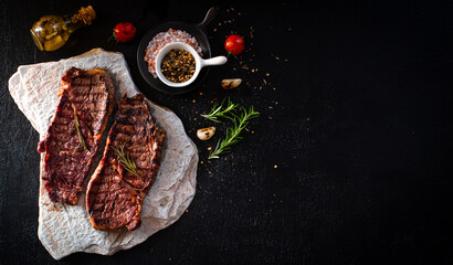 grilled beef steak  on a white stone on a black stone background Top view. Free space for your text.