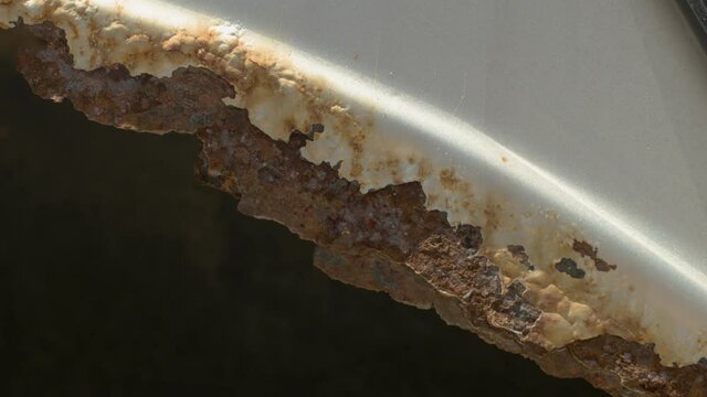 A close-up of rotted rusted metal in the fender of a car. The concept of the requirement of welding, restoration of old rusty cars. Timely technical auto service.