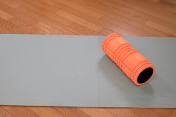 ヨガマットとストレッチするローラー