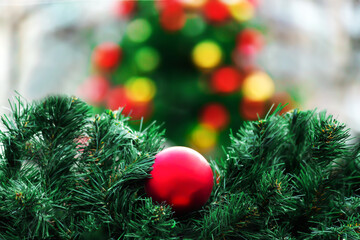 Red Christmas ball in spruce branches close-up on the background of a Christmas tree with red and yellow balls. A New Year's card. holiday background. Copy space.