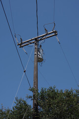 Low angle view of an electricity distribution pylon and power lines under blue sky