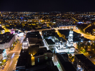 Dormition Cathedral illuminated in evening lights. Aerial view Kharkiv city downtown, Ukraine. Side view from air