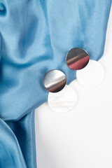 Top view of stylish earrings on wavy blue satin surface. Fashion and style concept. Top view