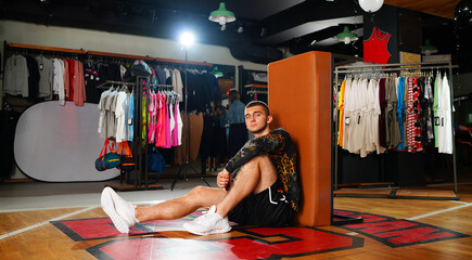 Positive young man looking sport shirt in bicycle store