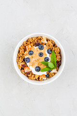 Bowl of granola with blueberries, peanut paste and yogurt on grey top view. - 441646688