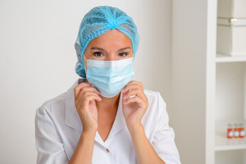The female doctor puts on a sterile protective mask. Coronavirus protection concept.