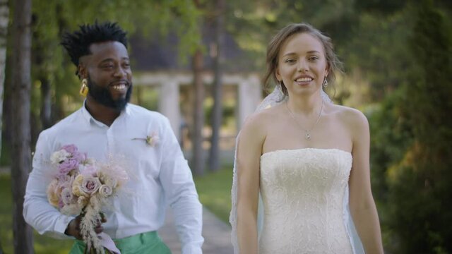 Meeting of the newlyweds before the wedding ceremony. The African American groom carries a bouquet of flowers to the bride, hugs her gently and looks lovingly
