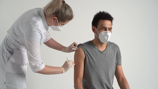 Caucasian young man receiving vaccine against coronavirus during mass vaccination campaign. Doctor using syringe to inject vaccine to patient prevent spread of virus covid19 on white background.
