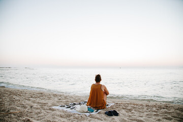 Peaceful morning at the beach. A woman waiting the sun rise while enjoying the breeze.
