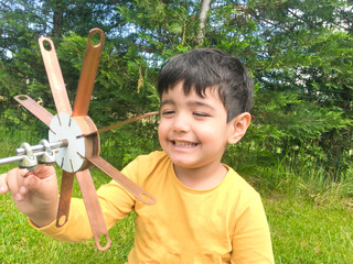 Boy holding colorful pinwheel in windy at outdoors. Children portrait and kids playing theme.