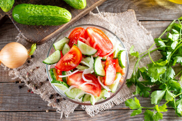 Tomatoes and cucumbers vitamin salad in a bowl on a table. Healthy food concept. Top view