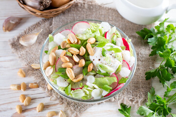 Fresh salad with cabbage, radish and peanuts. Healthy vegan lunch bowl on a white table. Top view