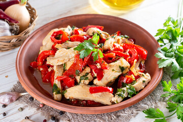 Fried chicken fillet strips with red bell pepper on a plate on a white table