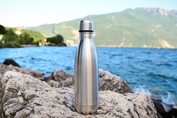 Steel eco thermo water bottle on the background of the lake in the mountains. Be plastic free. Zero...