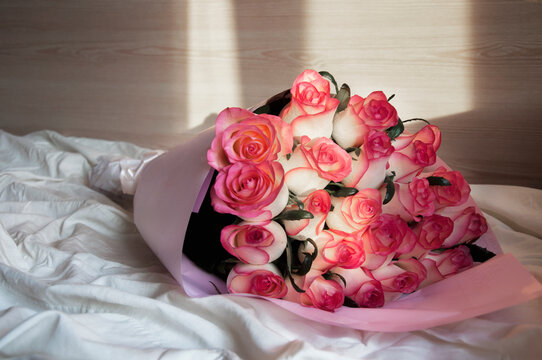 a bouquet of beautiful pink roses on a crumpled bed in the sun. High quality photo