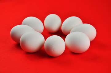 White chicken eggs on a red background.