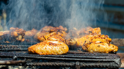 Roasted chicken wings on the hot grill; meat preparation process on the smoking grill