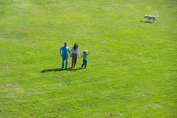 Fototapeta na wymiar Arial view of happy young parents playing with child outside in park.