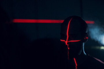 Man in dark with face illuminated scanning red laser on contour.