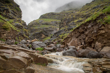 waterfall in the mountains with a cloudy weather