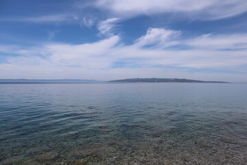 Seascape blue transparent water of the sea, white clouds in the blue sky on a summer sunny day,...