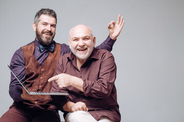 Happy young man with senior dad have fun watching funny video on laptop, smiling elderly father and grown son using internet on computer. Old and Young. New technology, oldness and lifestyle concept.