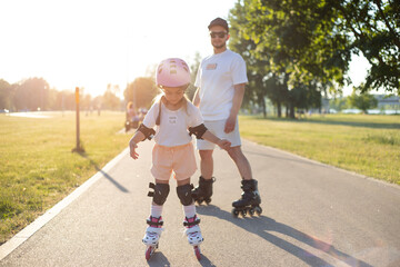 Dad with his little daughter on the skates. two people rollerblade.