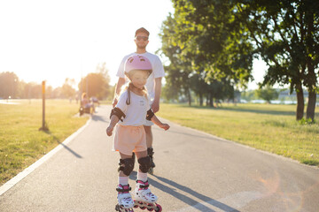 Dad with his little daughter on the skates. two people rollerblade.