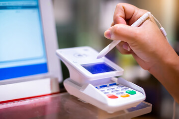 Selective focus to customer hand signing with electronic pen on a touch screen of credit card sale...