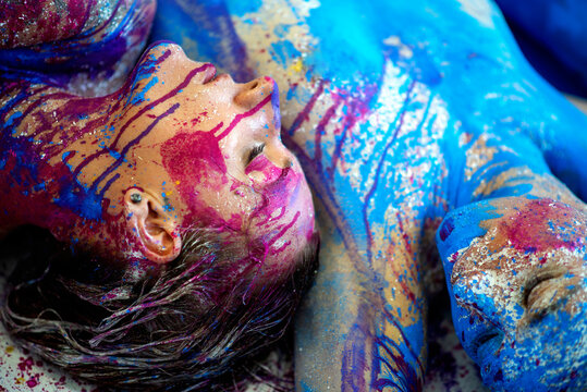 two strong colored portraits with blue purple magenta bodypainting, sexy brunette women, painted decorative, lying on the floor. Creative expressive abstract body painting art