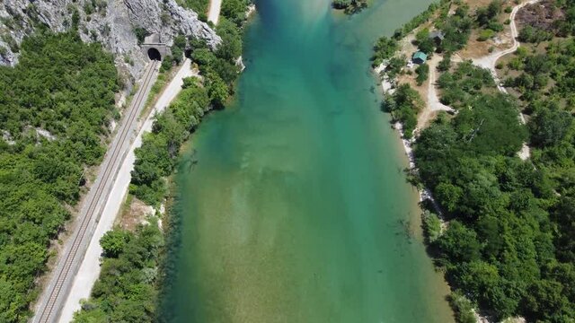 Aerial drone view of river and railway tracks near forest. Beautiful green river and forest in spring.	