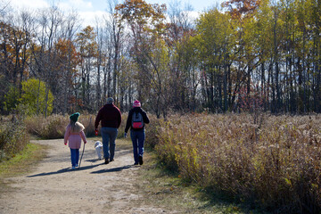 Toronto, Ontario / Canada - October 31, 2020: Family hiking in the forest footpath with social distancing.